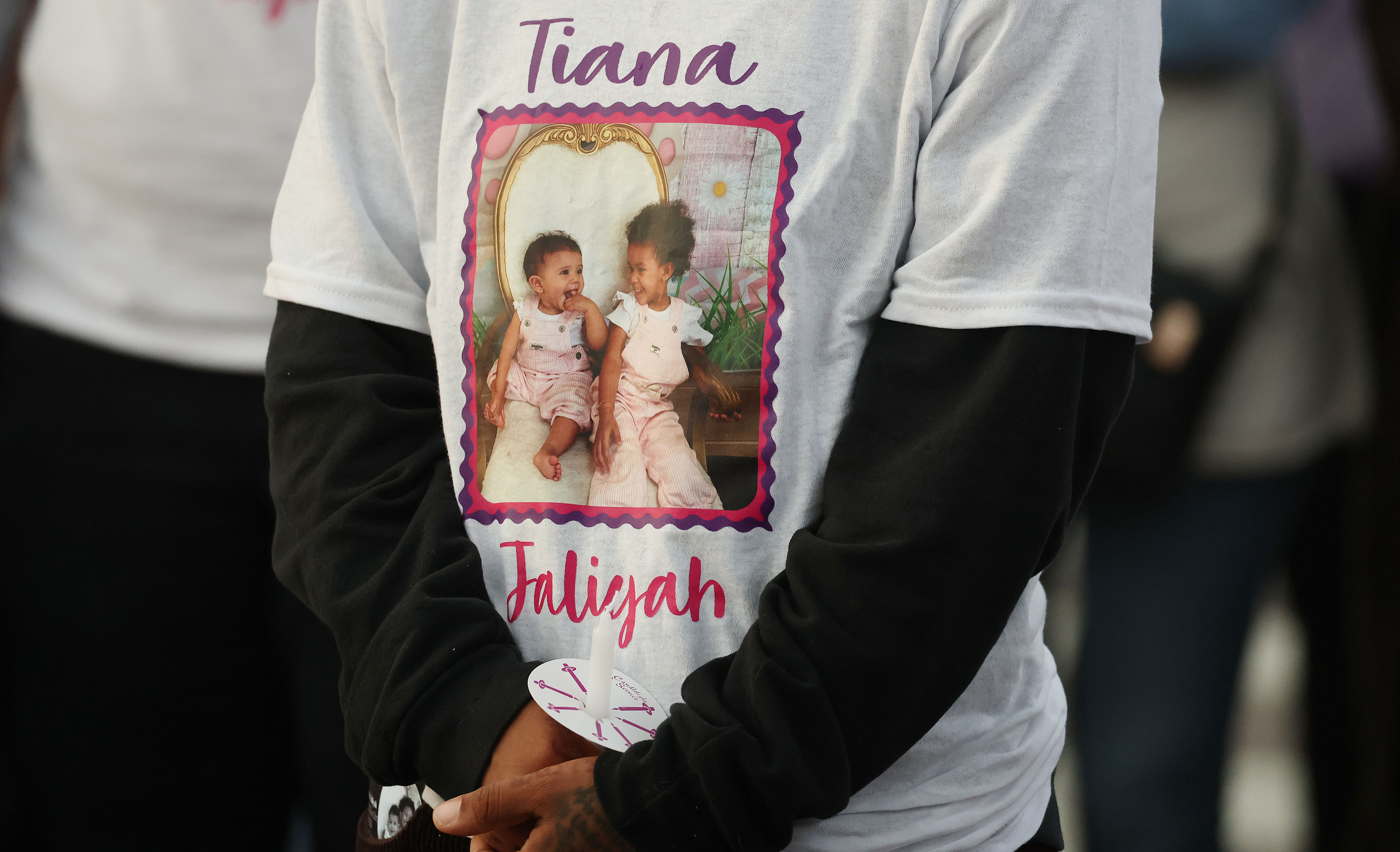 A mourner wears a memorial shirt during a community vigil...