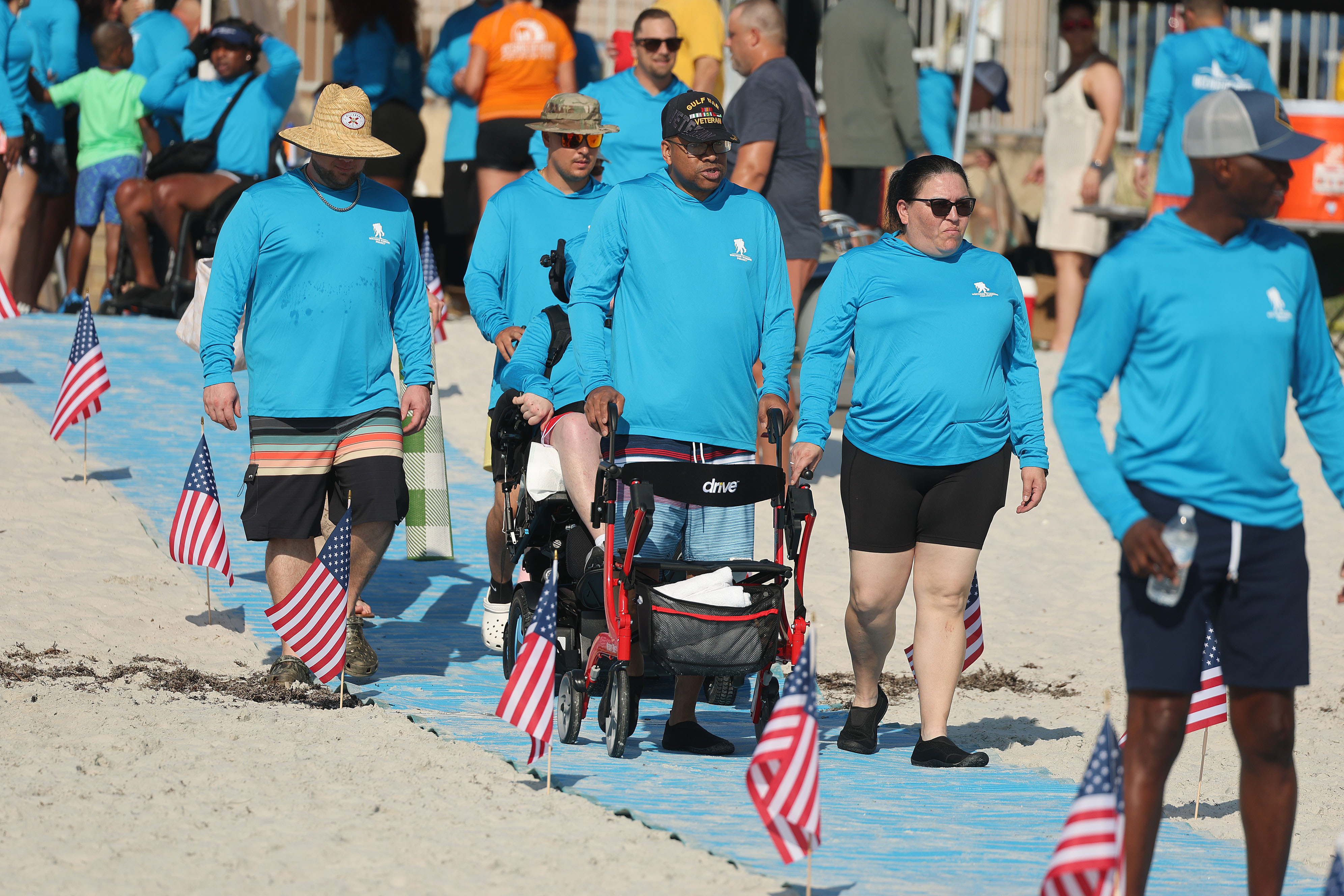 A wounded veterans and volunteers walk toward the beach to...