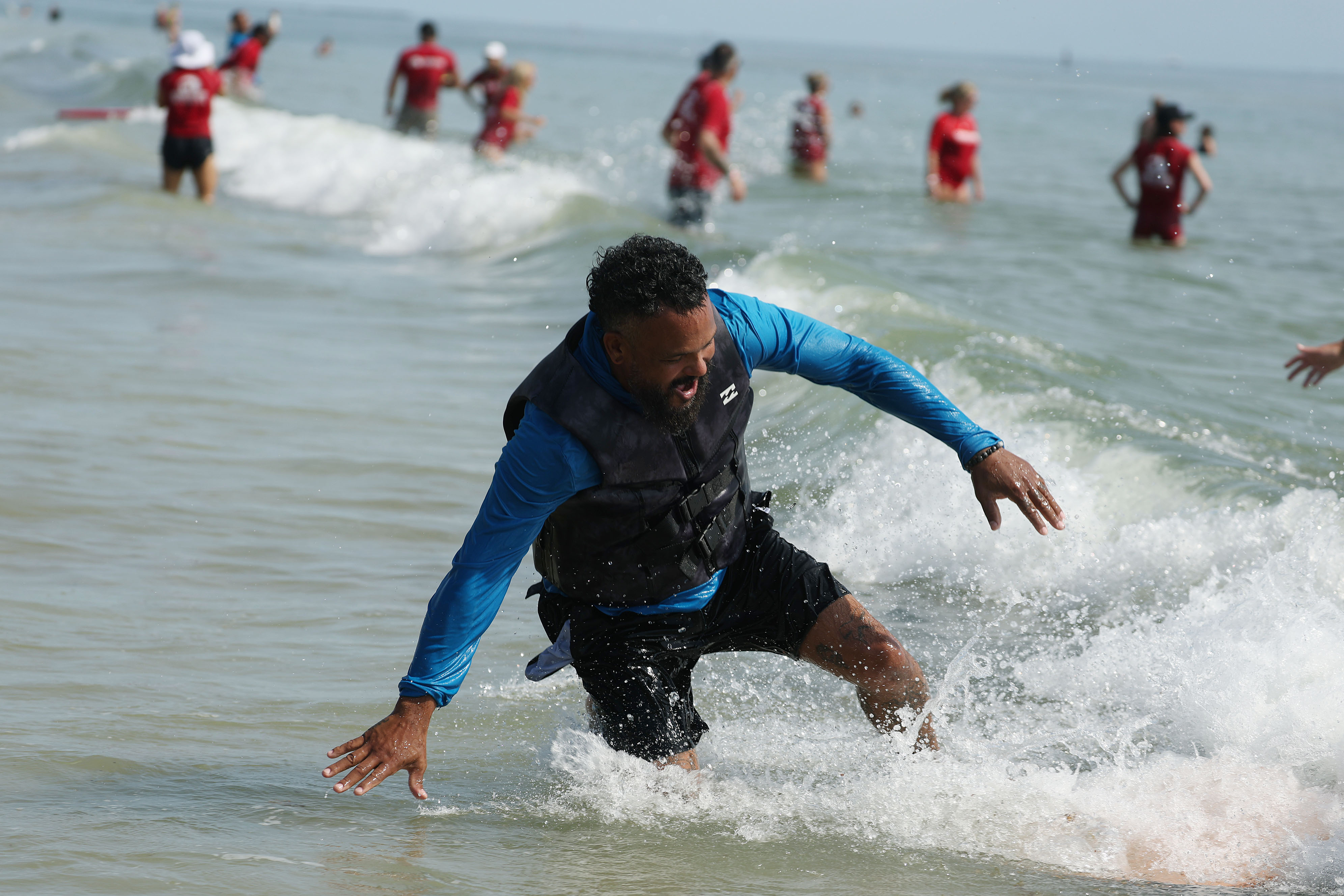 A wounded veteran jumps off his board in the surf...