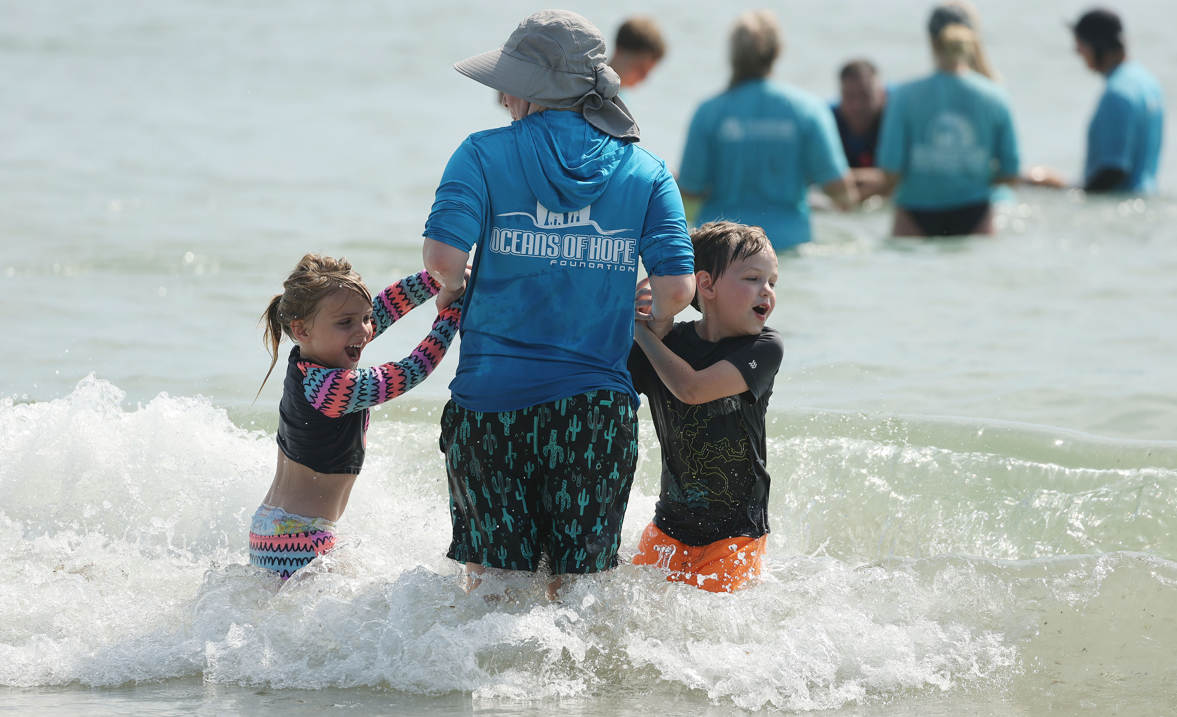 Children enjoy the waves as they watch wounded veterans surf...