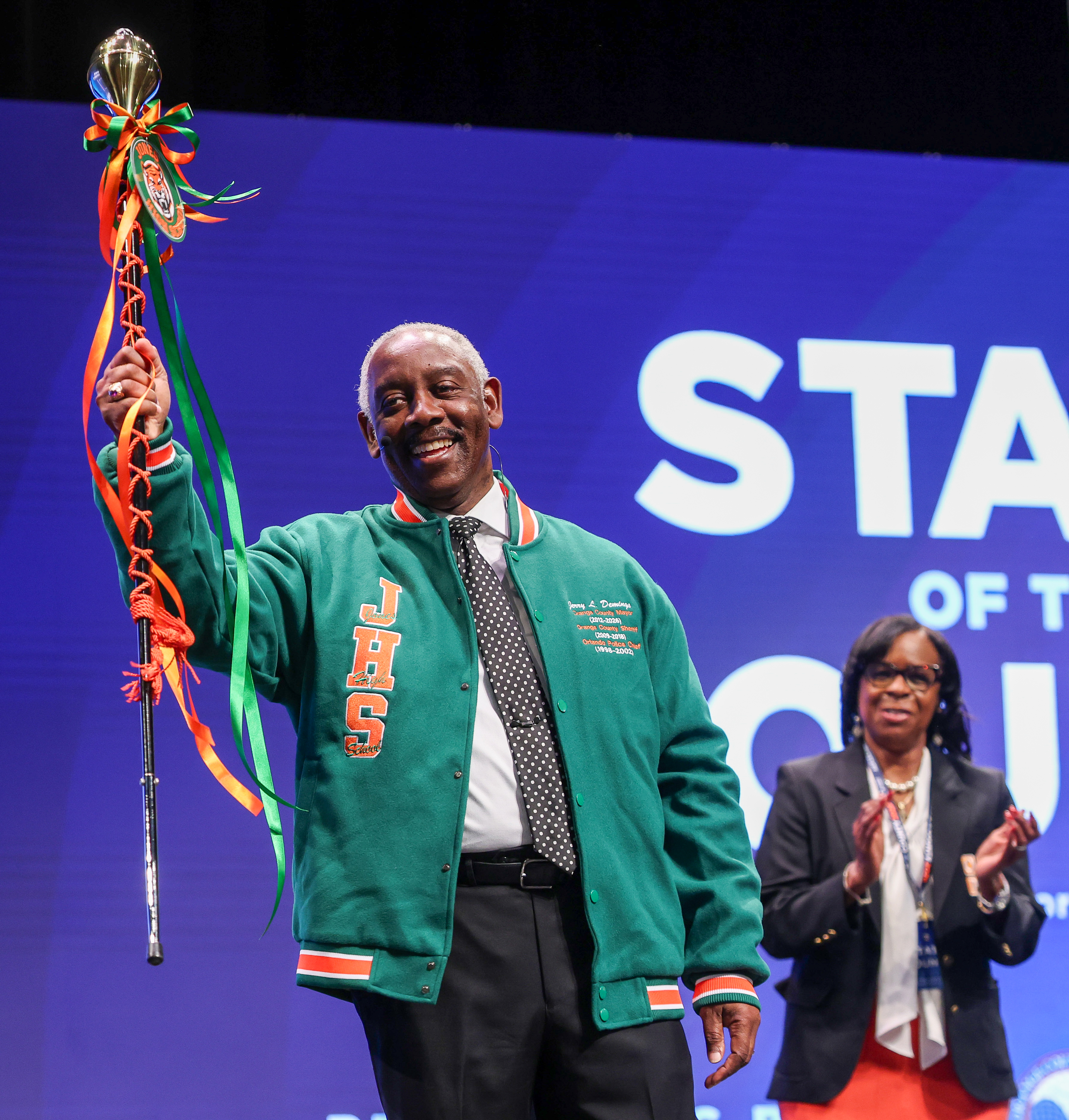 Orange County Mayor Jerry Demings holds up the drum major...