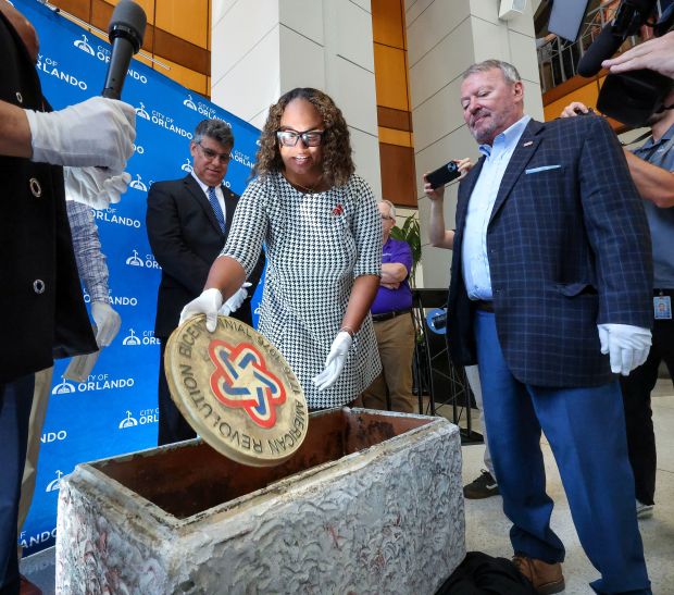 RETRO REVEAL Orlando city commissioner Shan Rose pulls out a 1976 plaque with Mayor Buddy Dyer, right, and commissioner Tony Ortiz, during the opening of a 50-year-old time vault at city hall ahead of America's 250th celebration Monday, June 29, 2026. The vault was sealed and buried at Lake Eola by the Kiwanis during the nation's Bicentennial celebration in 1976. The vault revealed a preserved collection of newspapers, photographs and Central Florida memorabilia.(Joe Burbank/Orlando Sentinel)