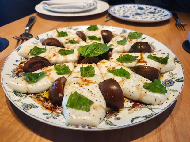 Rocca's Mozzarella Cart, a tableside prep of cheese, is paired with heirloom tomato basil and10-year-aged balsamic vinegar. There's a lot of wow factor in the $49 dish, shareable for four+ people. (Amy Drew Thompson/Orlando Sentinel)