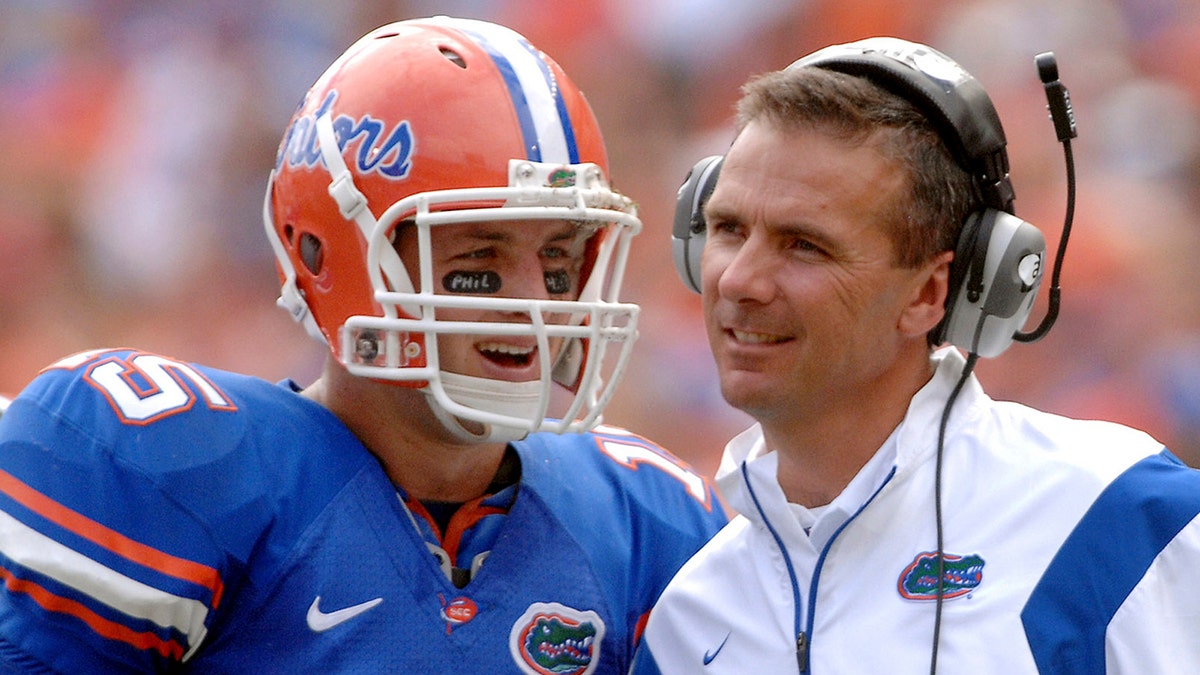 Florida quarterback Tim Tebow laughing with coach Urban Meyer on football field