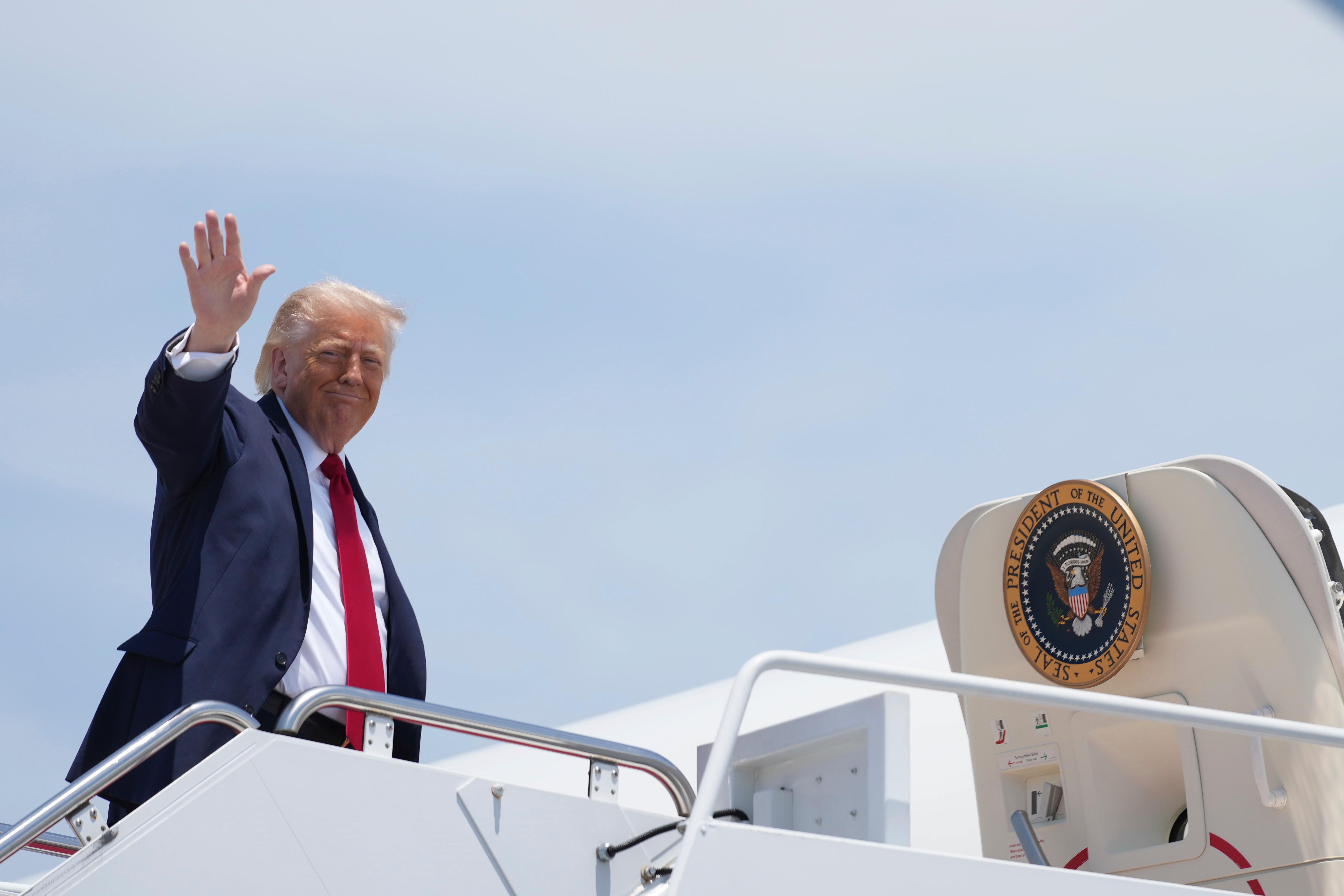 President Donald Trump waves as he boards Air Force One,...