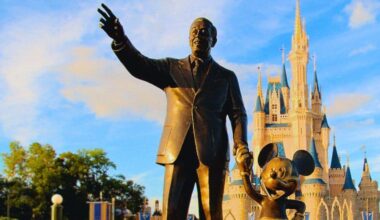 Walt Disney and Mickey Mouse statue in front of Cinderella Castle at Disney, with a bright blue sky and fluffy clouds above during the hot, humid summer months in Central Florida in Orlando. Florida resident Disney Summer Ticket