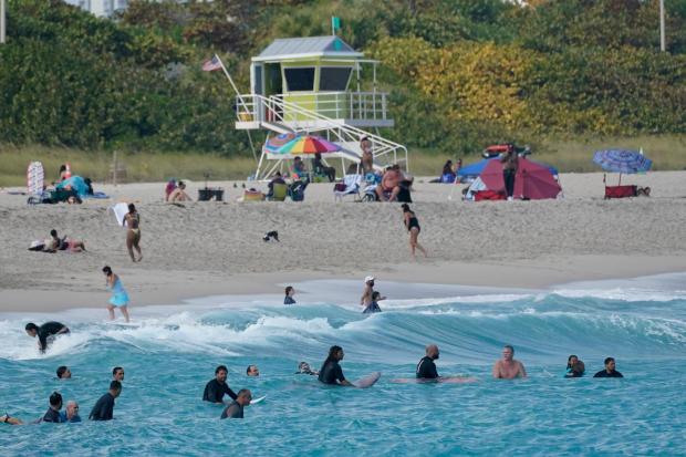 Surfers gather off shore waiting for a wave