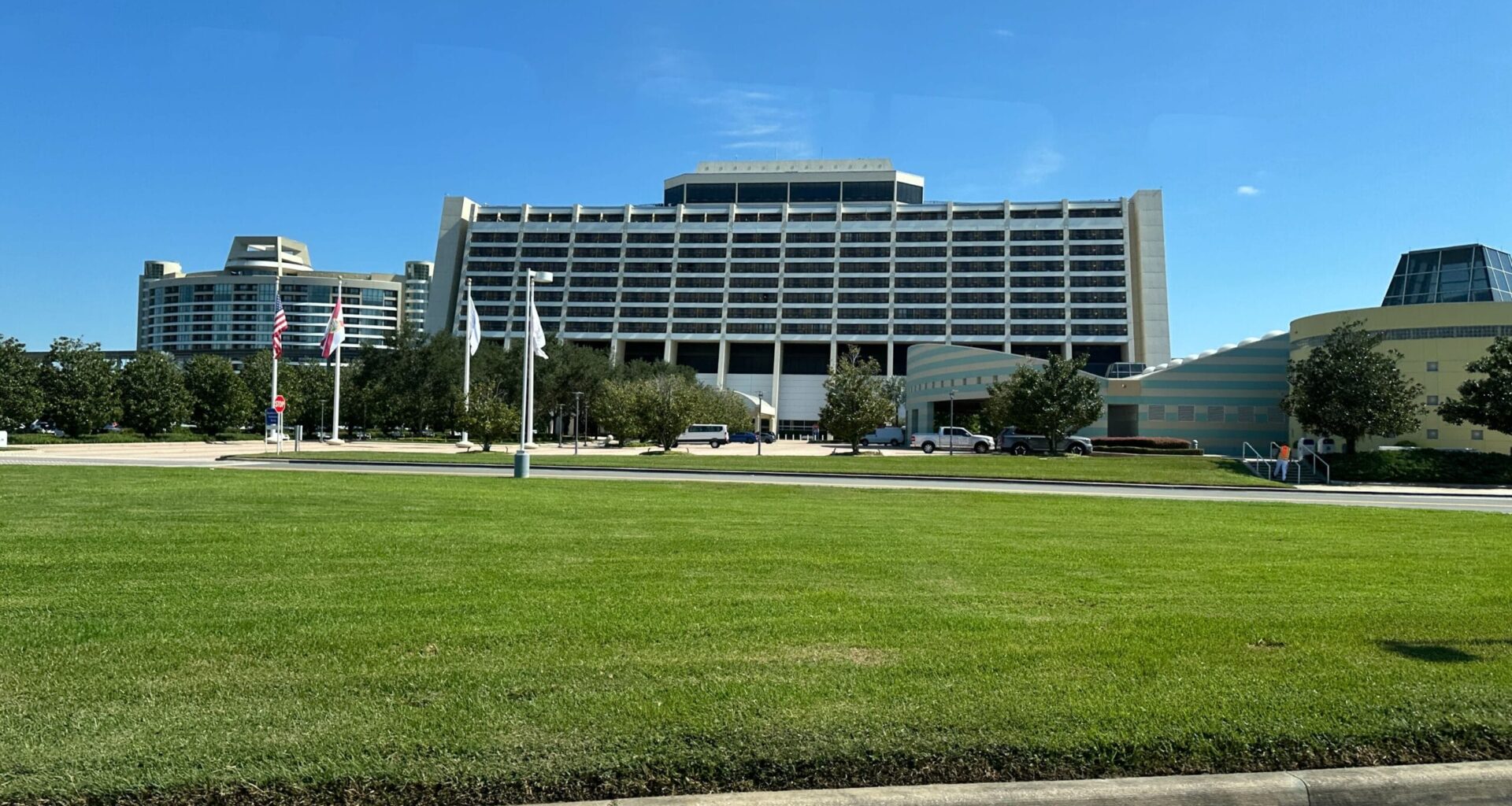 Large A-frame Contemporary Resort at Walt Disney World, American flags flying, lush green lawn, clear blue sky above.