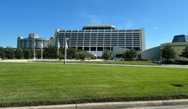Large A-frame Contemporary Resort at Walt Disney World, American flags flying, lush green lawn, clear blue sky above.