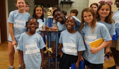 a group of smiling students holding a trophy