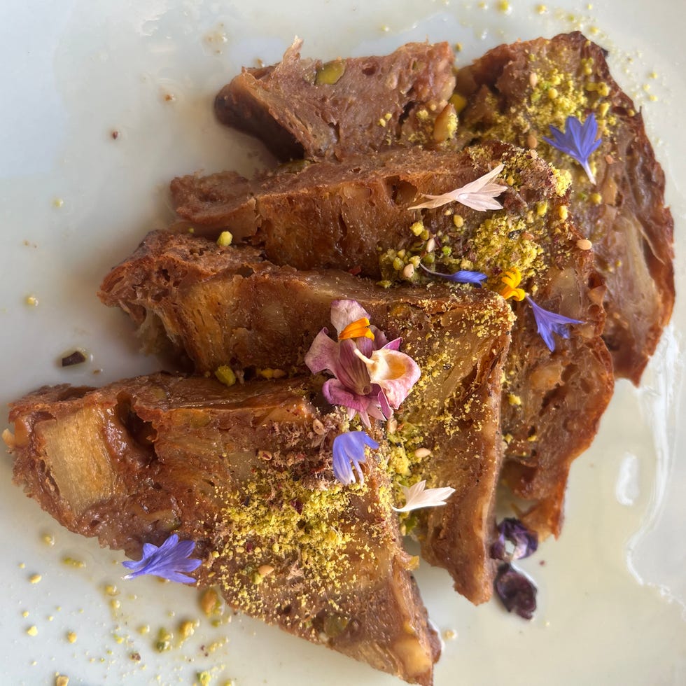 Slices of dessert topped with crushed pistachios and colorful edible flowers on a white plate. Slices of dessert topped with crushed pistachios and colorful edible flowers on a white plate.
