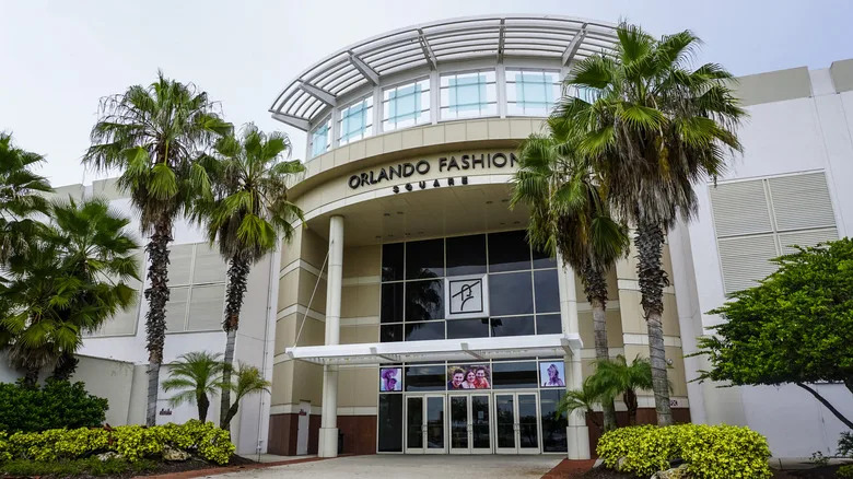 The front entrance of Orlando Fashion Square mall with palm trees and plants