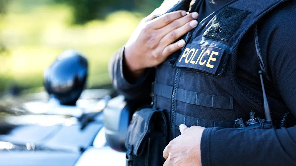 Police officer stands beside patrol vehicle in stock image