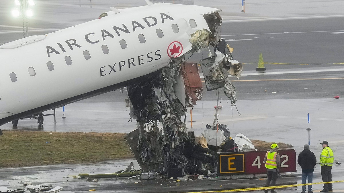 Officials standing near the site of an Air Canada jet and a Port Authority firetruck collision at LaGuardia Airport.