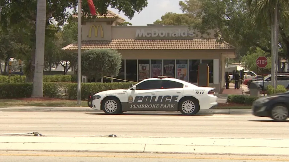 WSVN - PHOTO: Yellow police tape rings a McDonald's in Hallandale Beach, Florida, where a man and his 11-year-old daughter were injured when they were caught in the crossfire of a shooting on Saturday, June 27, 2026.