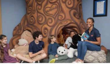 Children and a staff member gather for story time inside a reading space at A Kid
