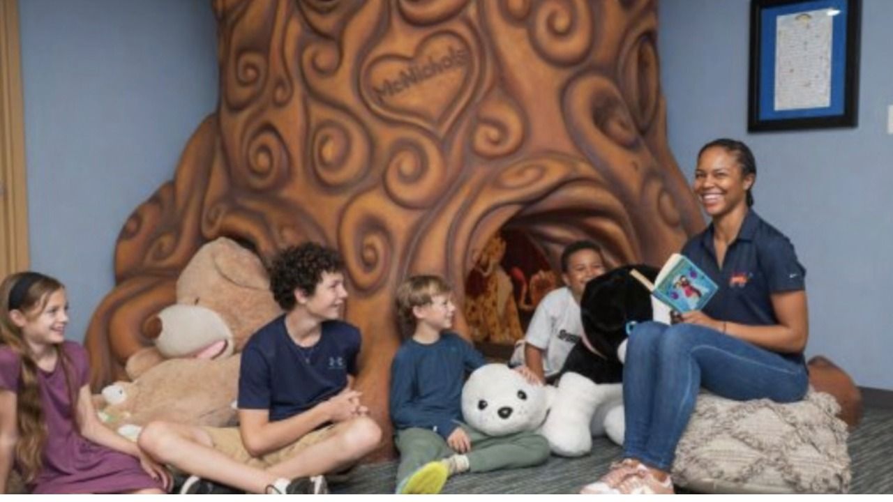 Children and a staff member gather for story time inside a reading space at A Kid