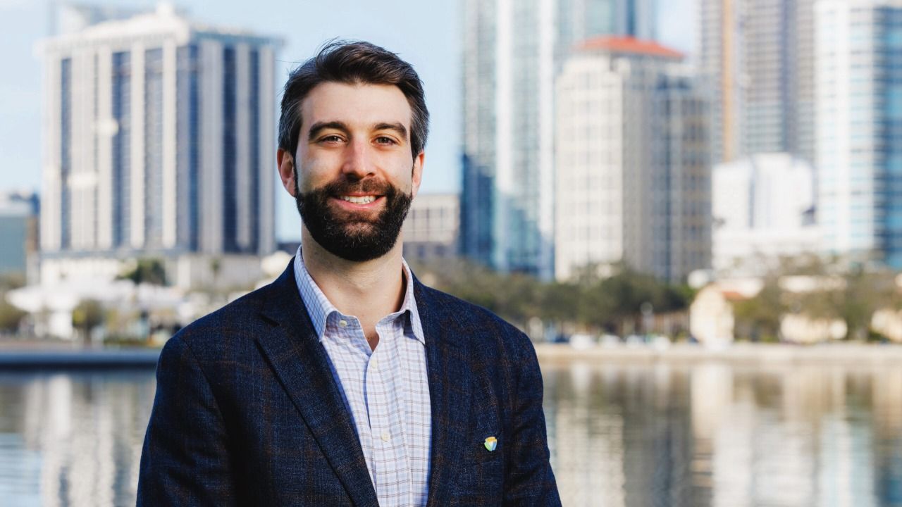 Mack Feldman, principal at Feldman Equities, stands along Tampa’s Riverwalk with the downtown skyline in the background.