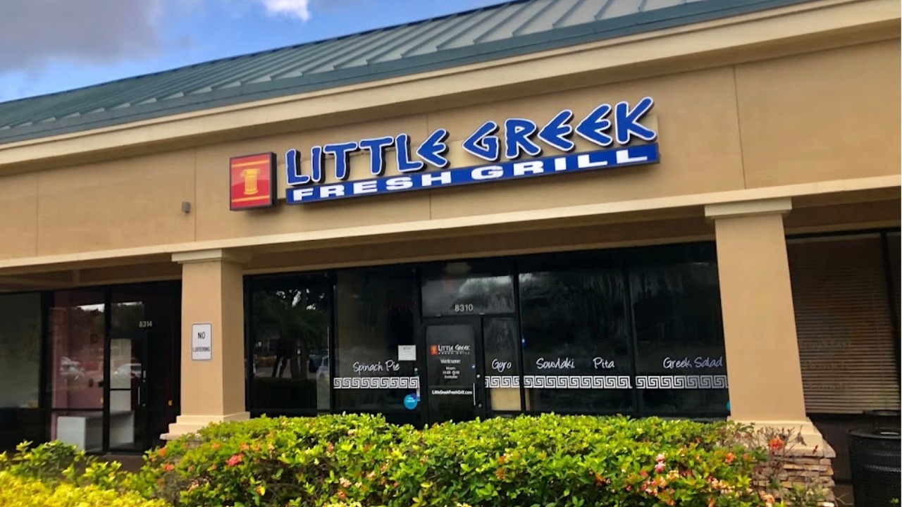 Exterior of a Little Greek Fresh Grill restaurant in a retail strip center with storefront signage and outdoor landscaping.