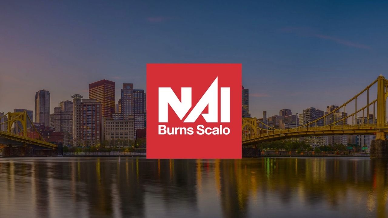 NAI Burns Scalo logo displayed over the Pittsburgh skyline and yellow suspension bridges along a riverfront.