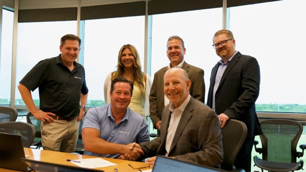 Brian Walker and Gary Tasman shake hands in a conference room after announcing the acquisition of Commercial Property Southwest Florida by NAI Burns Scalo.