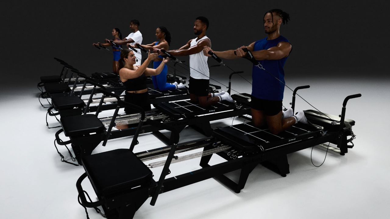 Participants perform a Solidcore strength-training class on reformer machines during a group workout session.