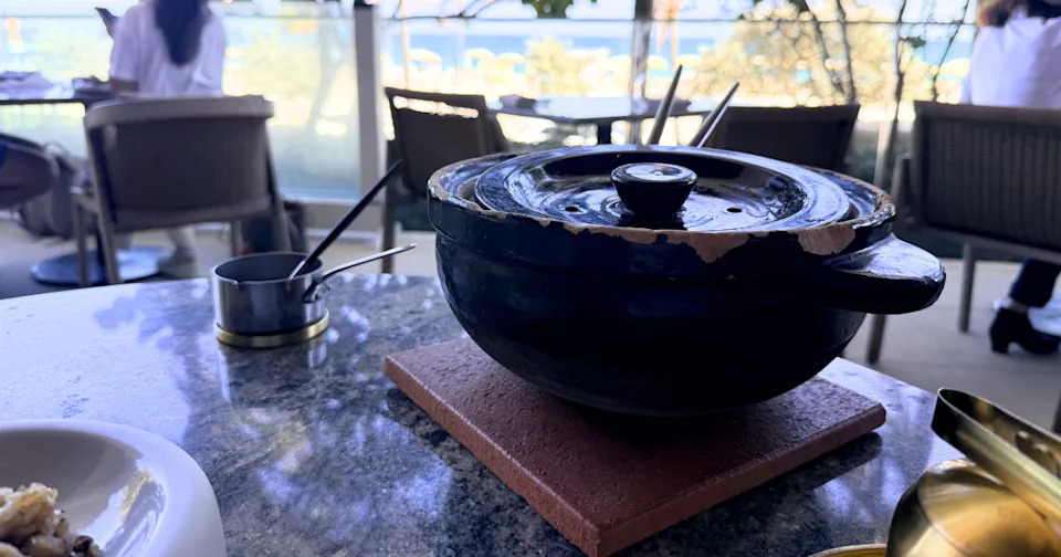 Koshihikari short-grain rice cooked with maitake mushrooms and finished with a Comté foam inside a traditional Japanese clay pot.