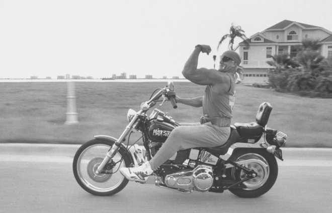 Wrestler Hulk Hogan flexing huge muscle on his left arm as he rides his Hulkster motorcyle on road in front of his home.  (Photo by Acey Harper/Getty Images)