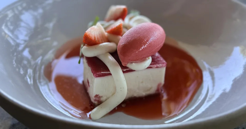 A beautifully plated artisan strawberry cheesecake dessert with delicate garnishes.