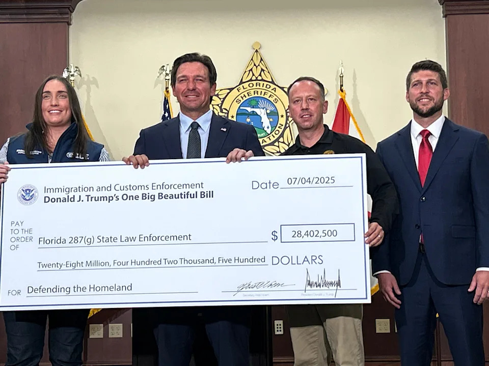 From left to right: ICE Deputy Director Madison Sheahan, Florida Gov. Ron DeSantis, Florida Department of Highway Safety and Motor Vehicles Executive Director Dave Kerner, and Florida Attorney General James Uthmeier, holding up a check for "Defending the Homeland" at a press conference in Tallahassee, Florida on Sept. 26, 2025.