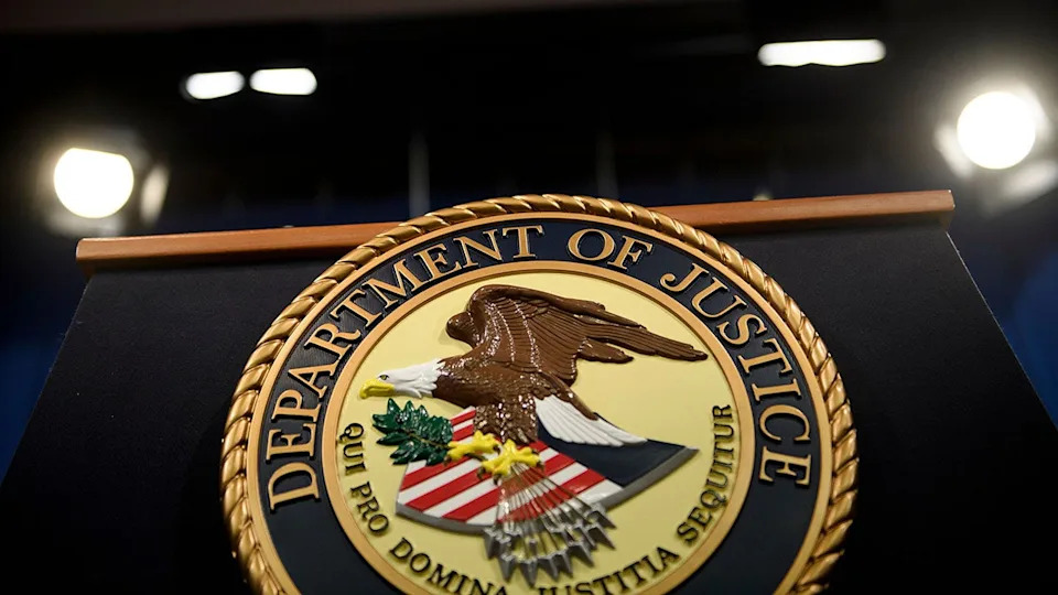 US Attorney General William Barr standing at a podium in a lecture hall at the Department of Justice