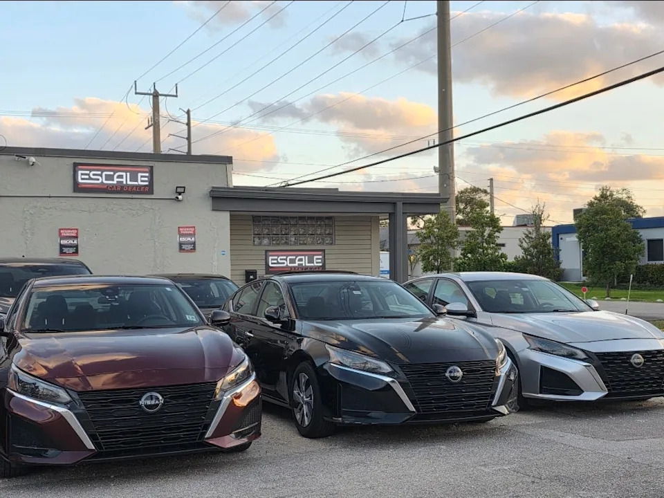 Row of three Nissan cars parked in front of an office building.