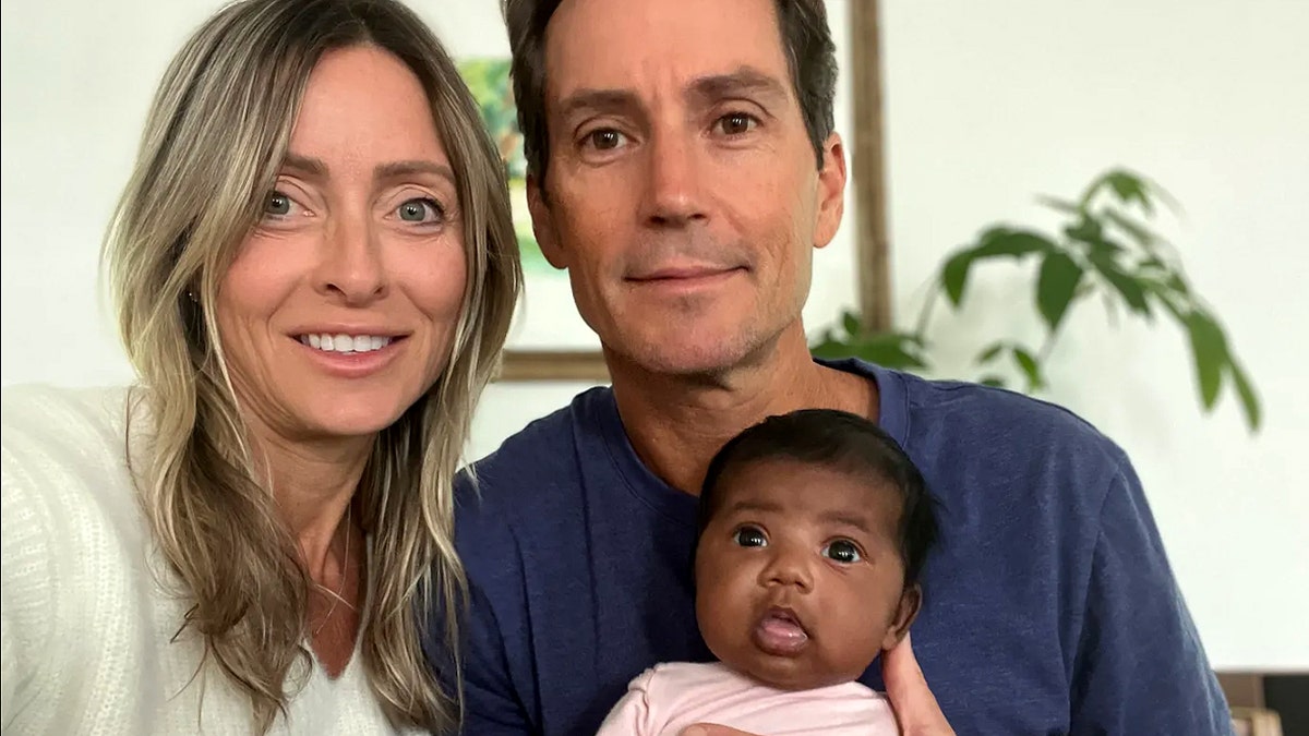 Two adults holding a baby in a family setting