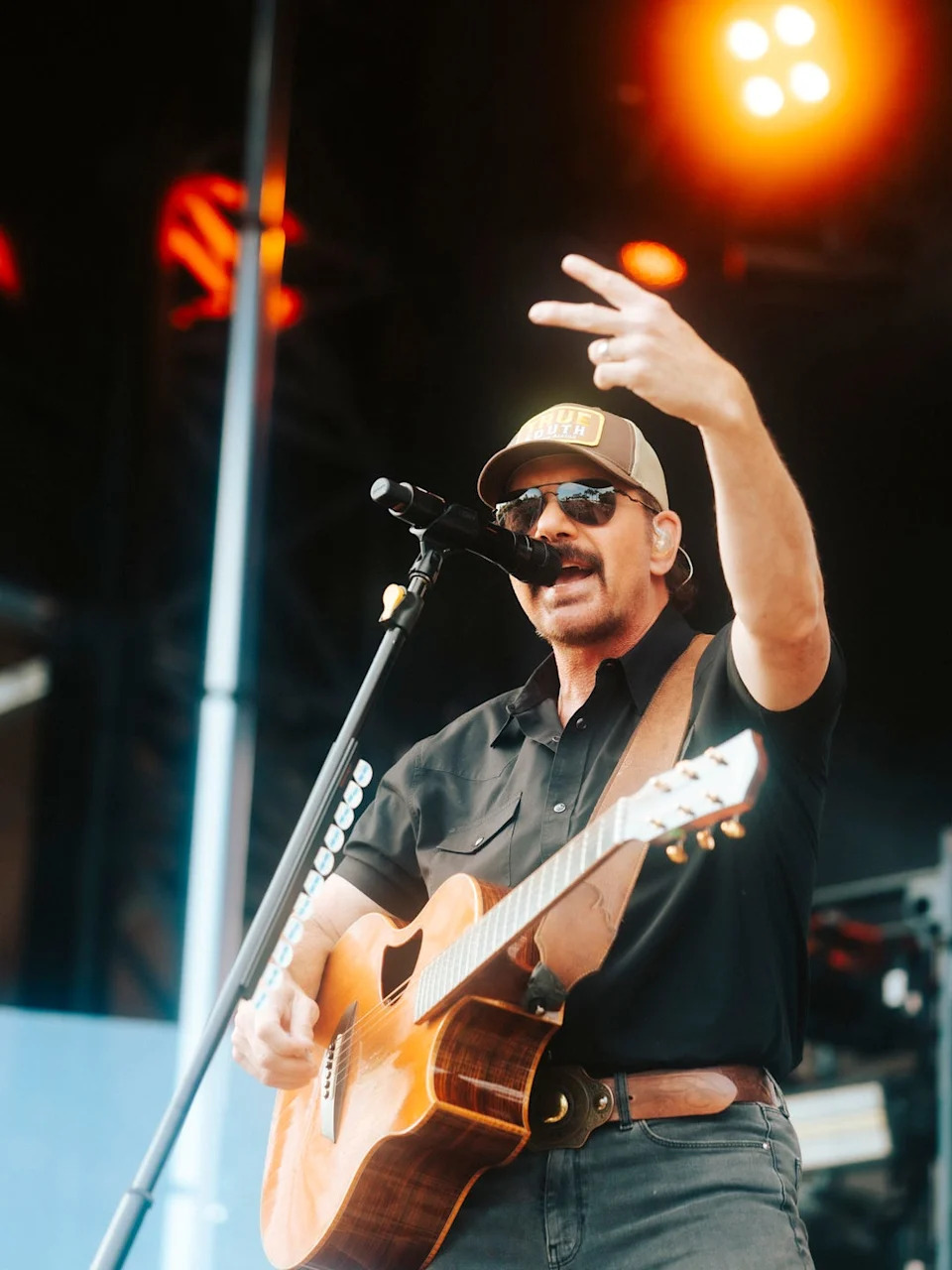 Musician performing on stage with guitar and microphone