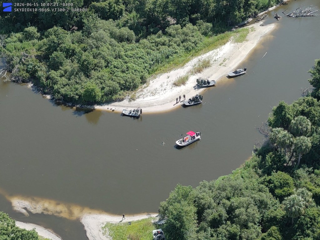 Aerial view of boats gathered on a river for a search and rescue operation.
