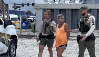 Deanna Harrell, accused of a driving a pickup truck into a tollbooth and killing the attendant, is led away in handcuffs from the Dunlawton beach ramp in Daytona Beach Shores.