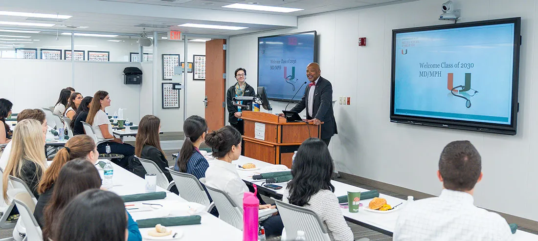 Dean Ford presents at the front of a classroom with slides displayed during the University of Miami Miller School of Medicine M.D./M.P.H. Class of 2030 orientation.
