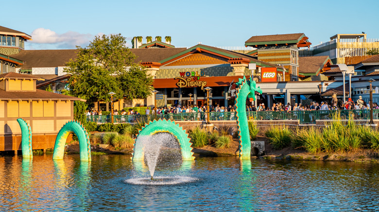 Disney Springs in Lake Buena Vista, Florida with water fountain and green dragon in the water and shops in the background