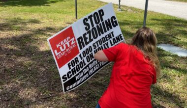 Demelza Hays puts up a sign in opposition to a a plan to build a private school in Lutz. (Spectrum News)