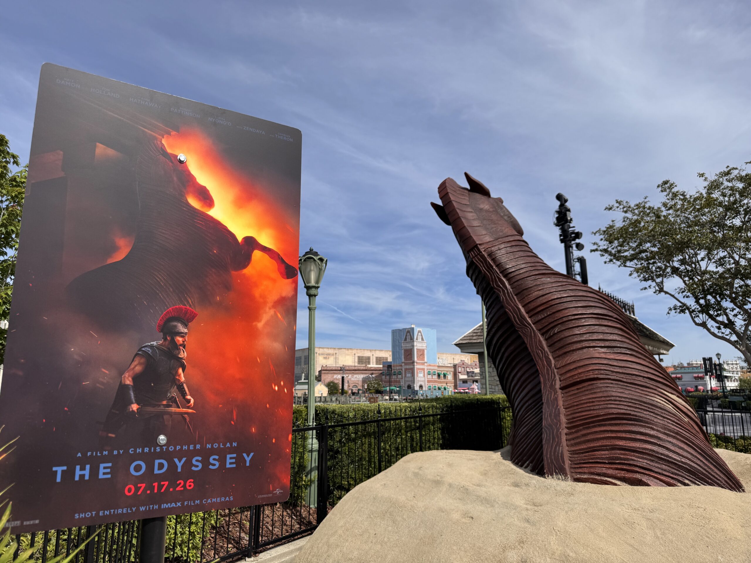 A large wooden horse sculpture, a reference to the Trojan Horse, emerges from the sand. This promotion is for The Odyssey, which follows the story of Odysseus, the king of Ithaca, on his journey to get home to his family after the Trojan War. It takes place in Ancient Greece.