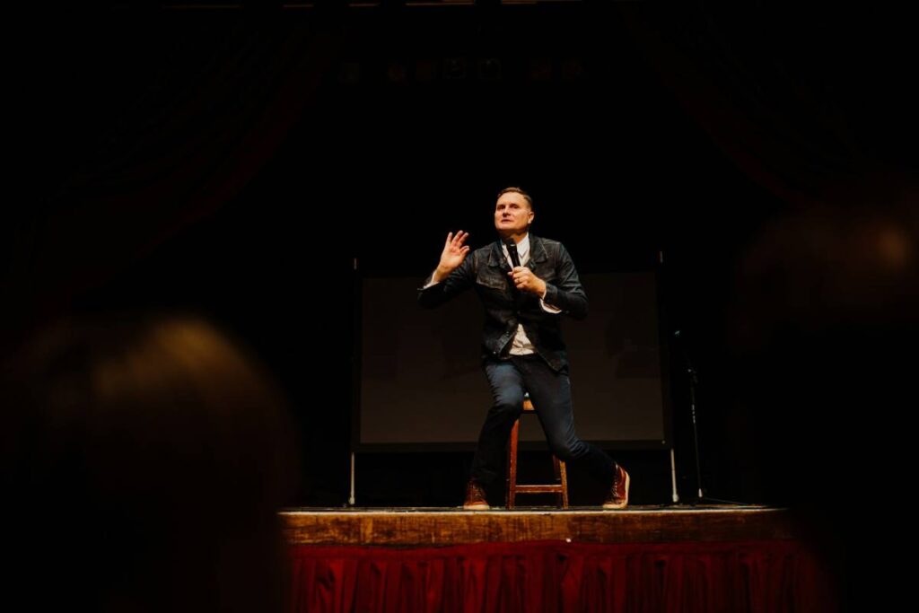 A stand-up comedian performing on an elevated stage