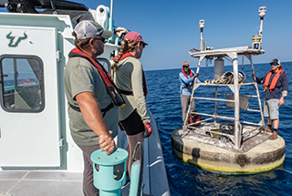 Researchers board a buoy used to monitor ocean conditions in the Gulf.