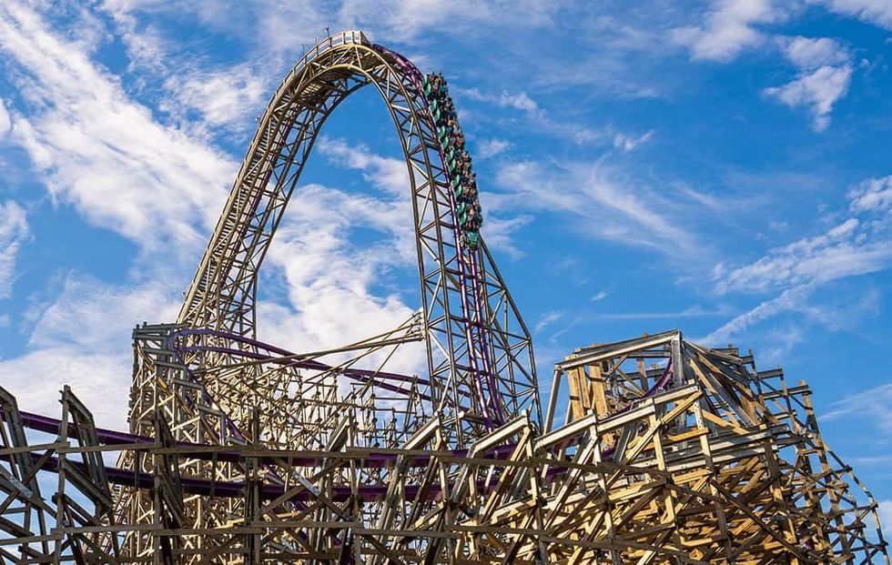 Tall wooden roller coaster called Iron Gwazi against a bright blue sky with clouds at Busch Gardens Tampa Bay