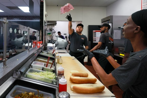 Brandy Duncan prepares to catch the meat from Eric Diaz as they make a sub at Laspada's in Fort Lauderdale. Customers say they enjoy the meat-slinging show. (Mike Stocker/South Florida Sun Sentinel)