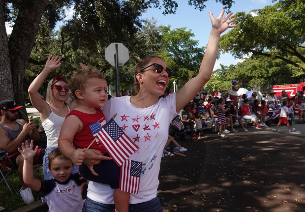 Felicia Trainor and son Tyson wave to fire trucks during the 2023 Fourth of July parade in Plantation. (Joe Cavaretta/South Florida Sun Sentinel)