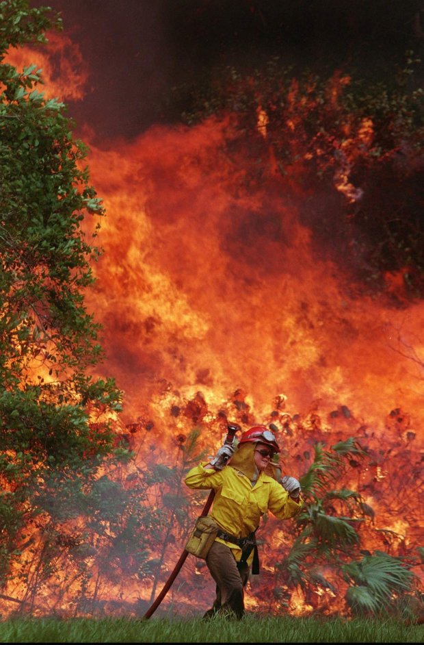 Firefighter Amy Midgett retreats from a wall of flames along US-92 just west of Daytona Beach on June 28, 1998. A series of backfires were started along the highway by the forestry service in an effort to stop eastward movement of the fire. (AP file) 