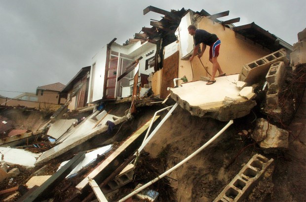 Braving high winds, Troy Taynton, of Satellite Beach, Fla, checks the remains of his neighbors home on Sept. 26, 2004. The storm surge from Hurricane Jeanne destroyed a pool, concrete slabs and a home on Shell Street. (Orlando Sentinel file)