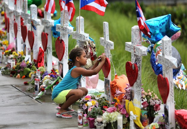 Mekiha Thomas, 7, signs one of the 49 crosses at the makeshift memorial outside Orlando Regional Medical Center on June 19, 2016. The crosses honor each victim in the Pulse massacre. (Joe Burbank/Orlando Sentinel file)