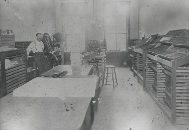 Edward Harrington stands in the composing room of the Orange County Reporter circa 1881. He is surrounded by large tables and printing equipment. (Courtesy Orange County Regional History Center)
