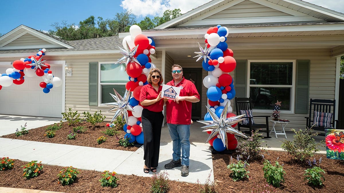veteran and wife in front of home